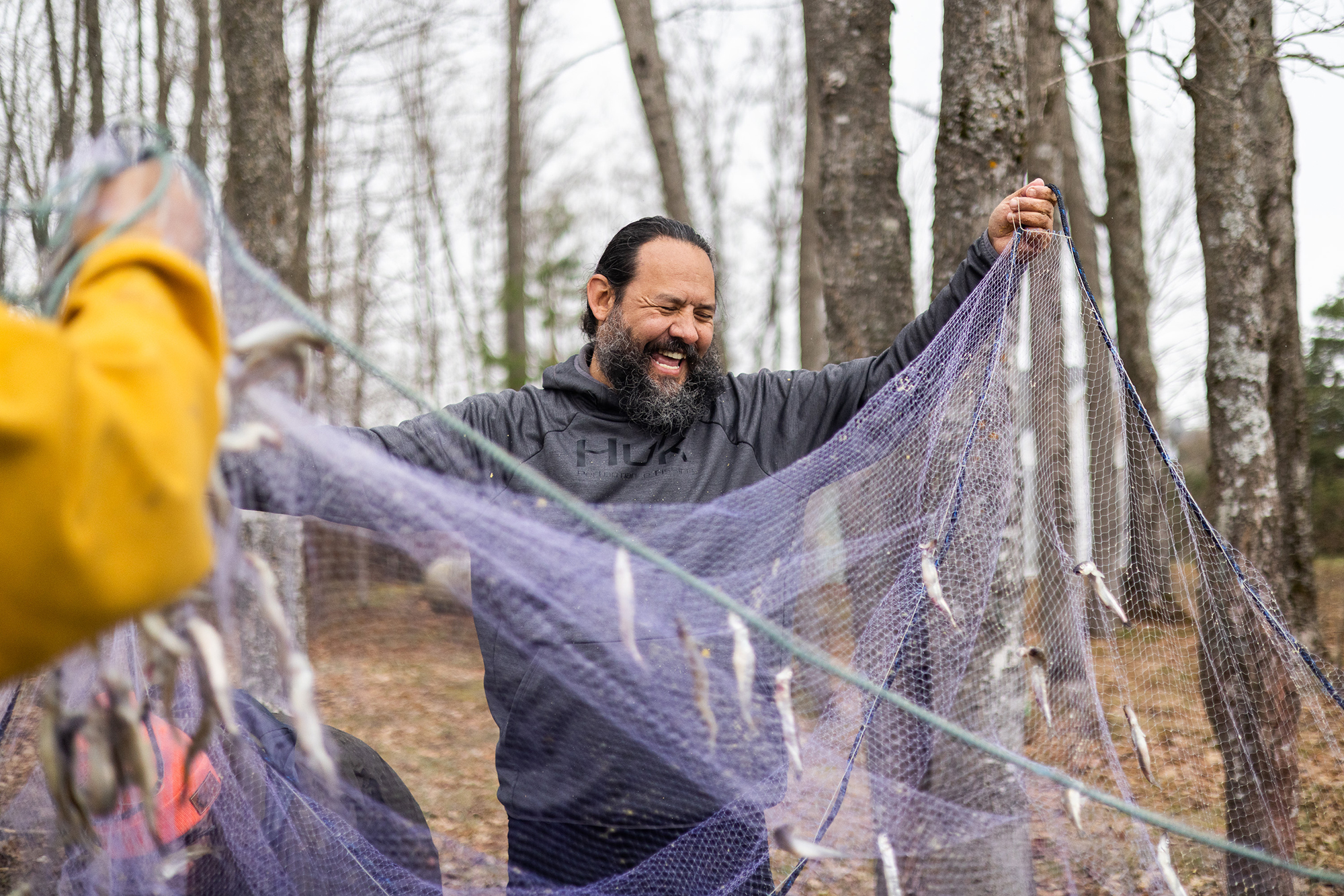 A man laughing as he holds up a fishing net.